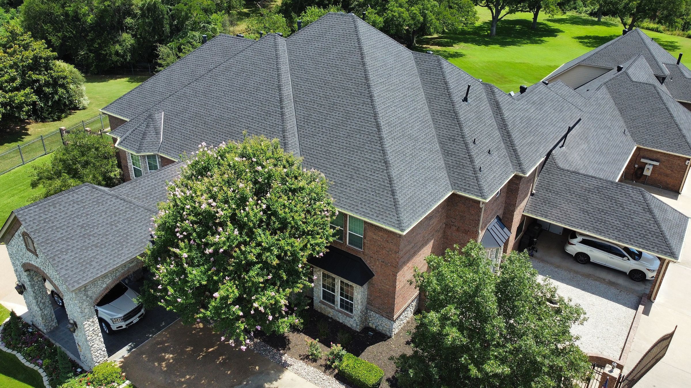 Aerial view of a finished charcoal shingle roof on a large brick home