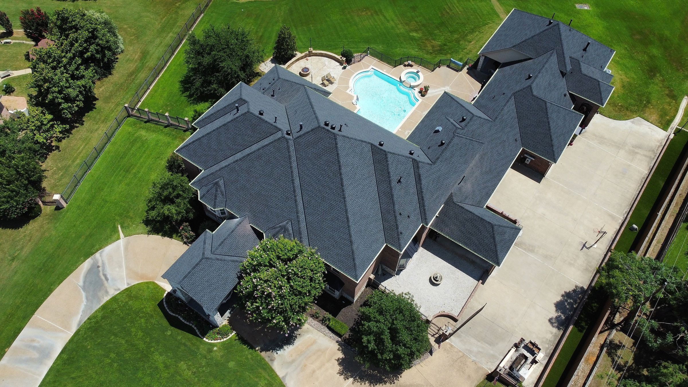 Top-down view of a finished shingle roof on a home with a backyard pool