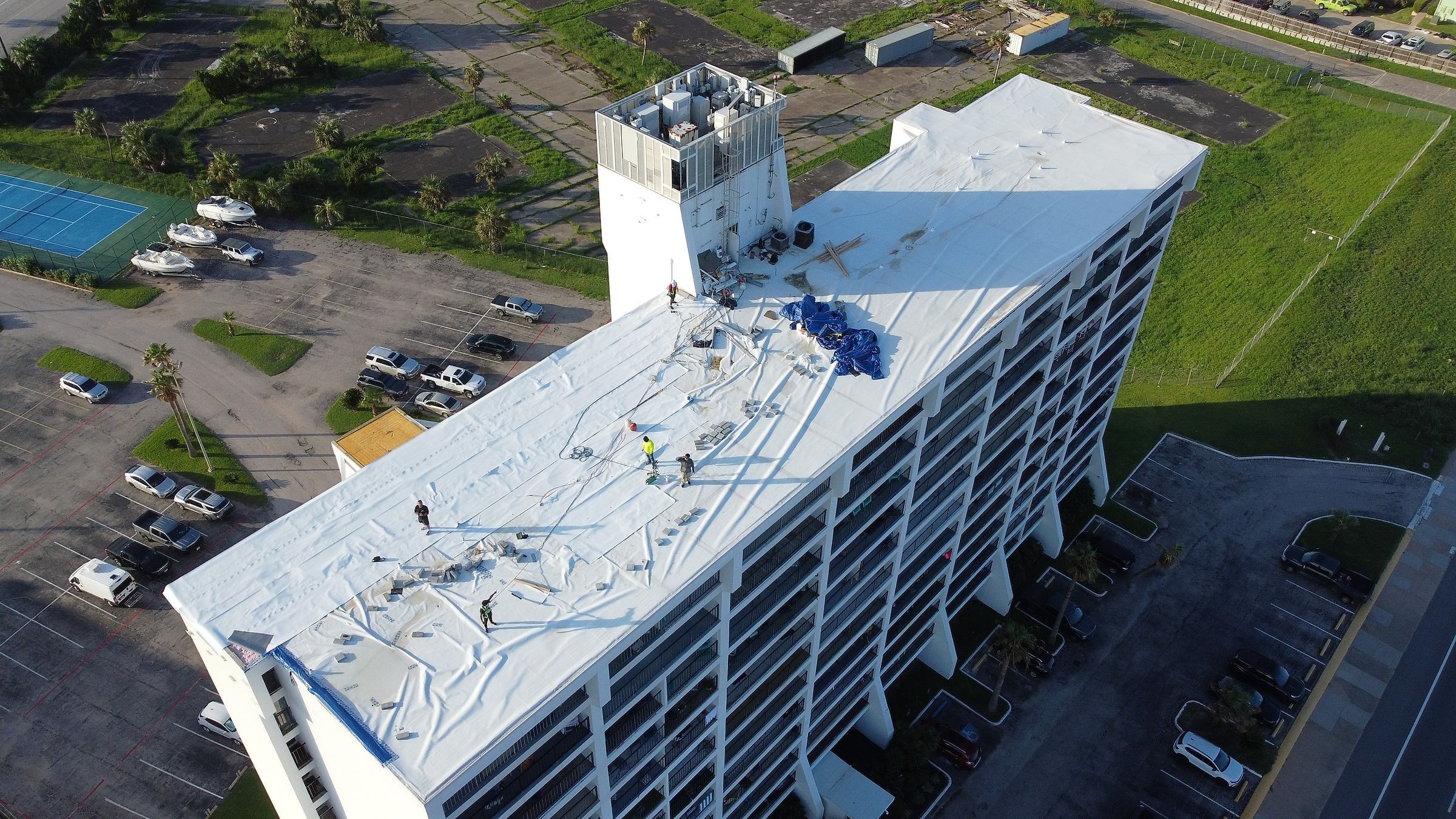 Crew making an emergency temporary repair on a hurricane-damaged TPO roof of a high-rise, Galveston, TX
