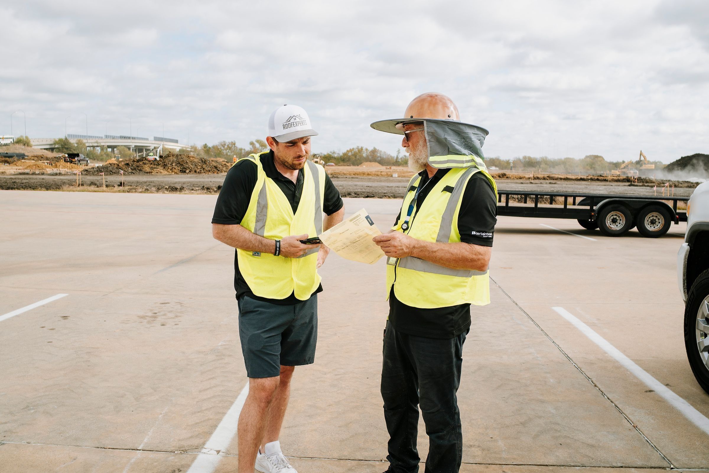 Roof Experts owner reviewing paperwork with the crew foreman on a commercial job site