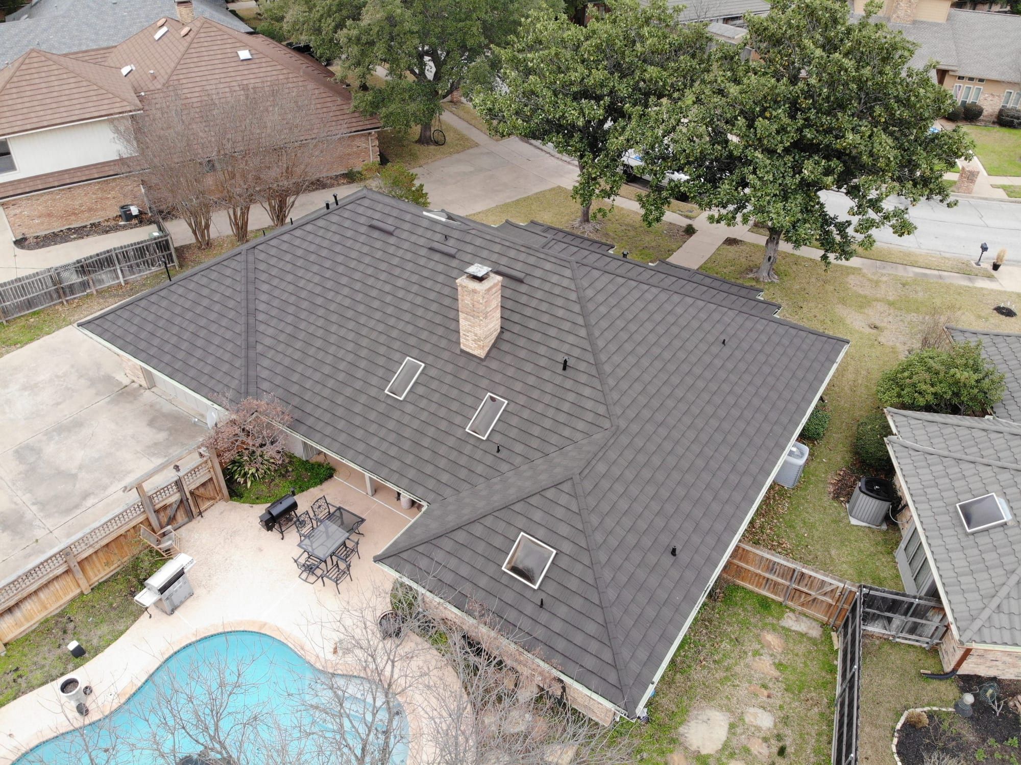 Gray stone-coated steel roof on a single-story home with a backyard pool, viewed from the air