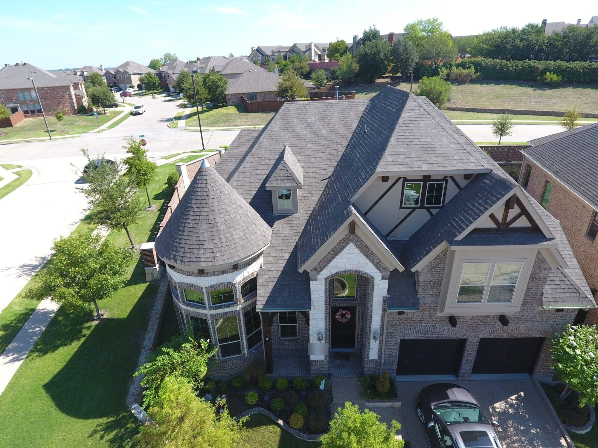 Two-story stone home with a turret and a freshly replaced shingle roof