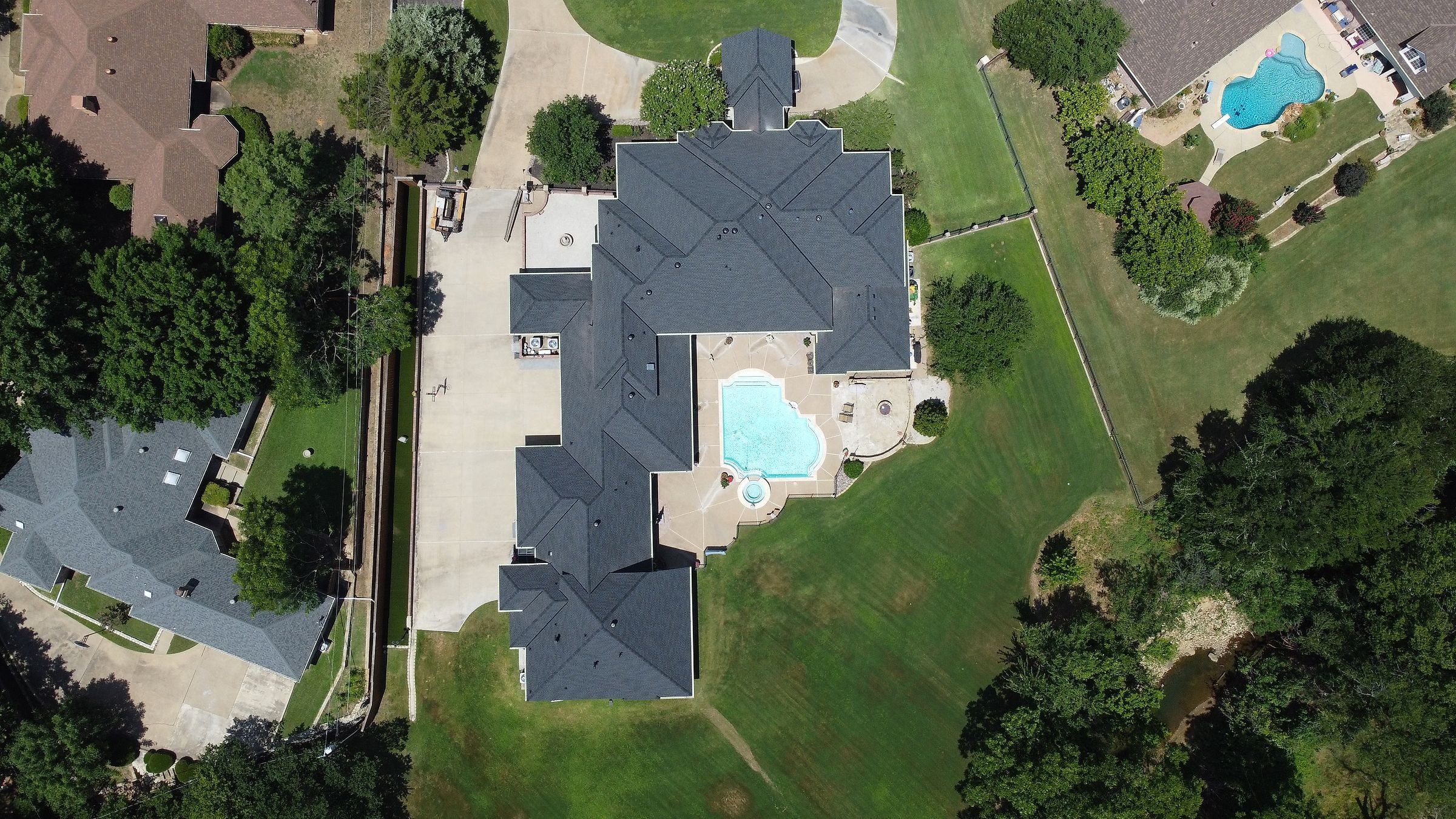 Charcoal shingle roof on a large home with a backyard pool, seen from above