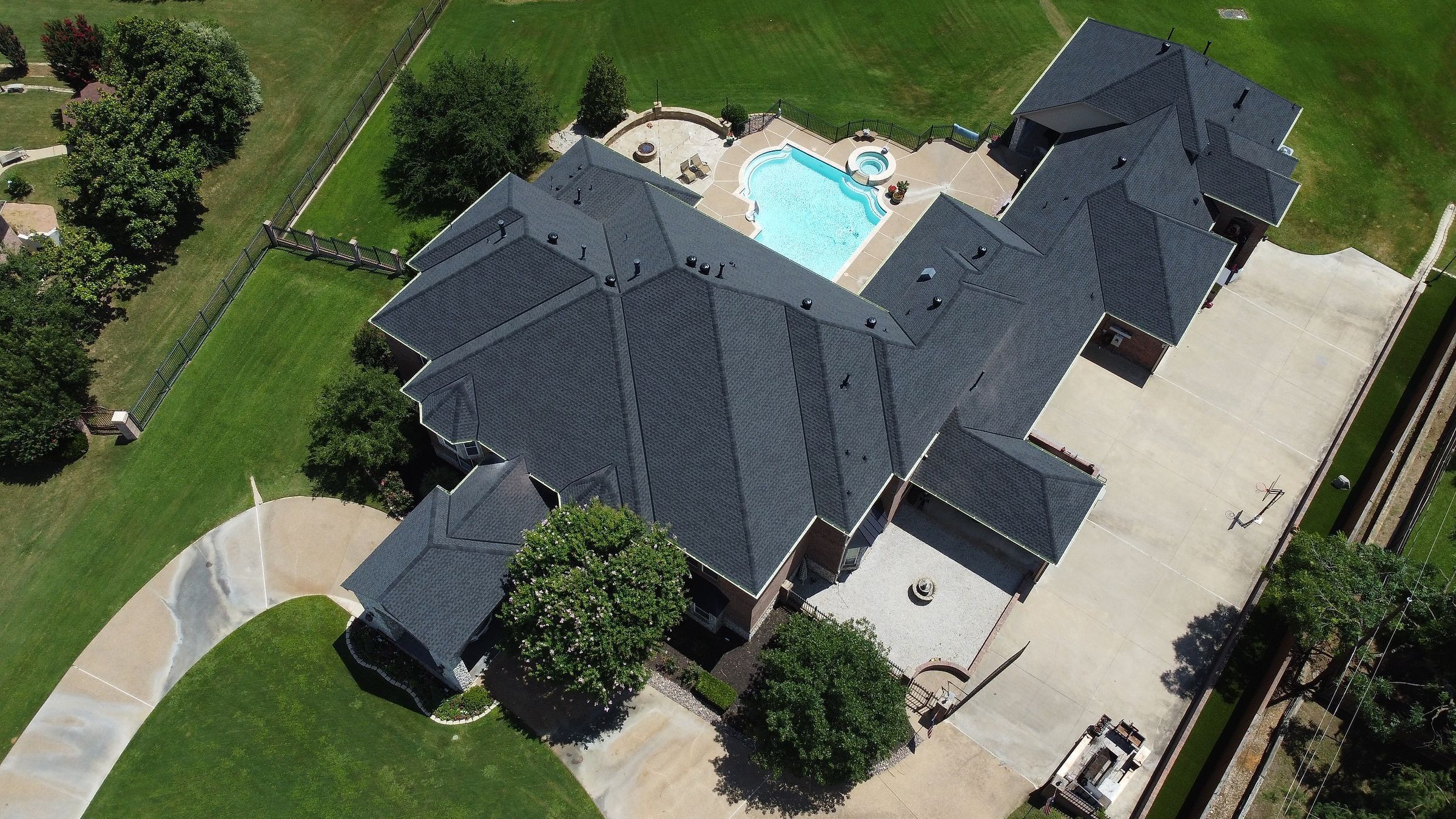 Charcoal shingle roof on a large home, with the pool and patio behind it