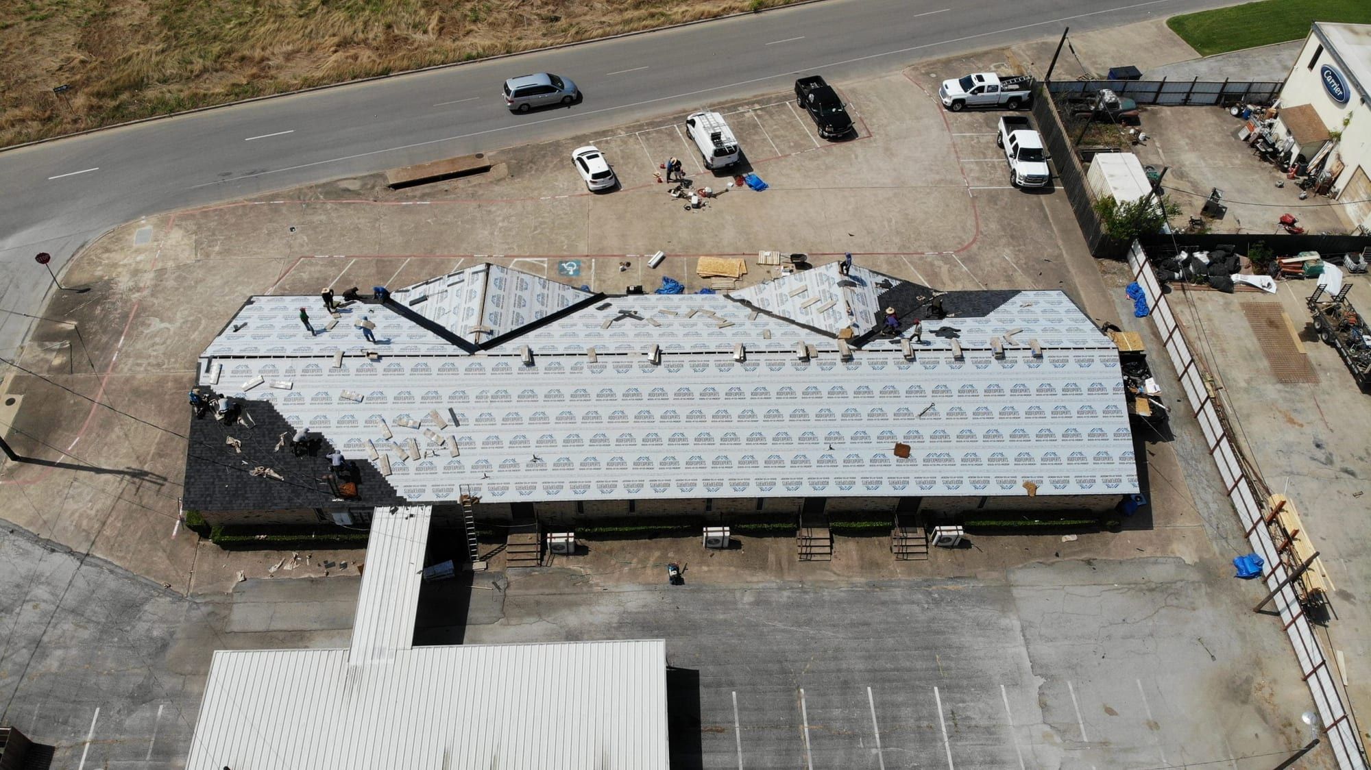 Strip-center roof wrapped in new underlayment during a commercial reroof