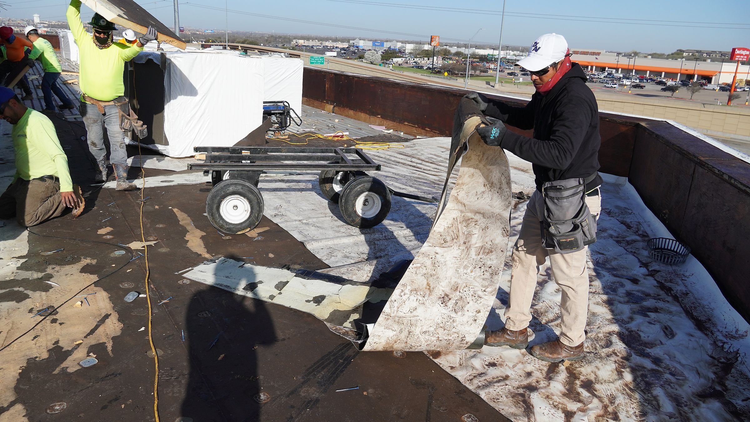 Roofer pulling up an old commercial roof membrane