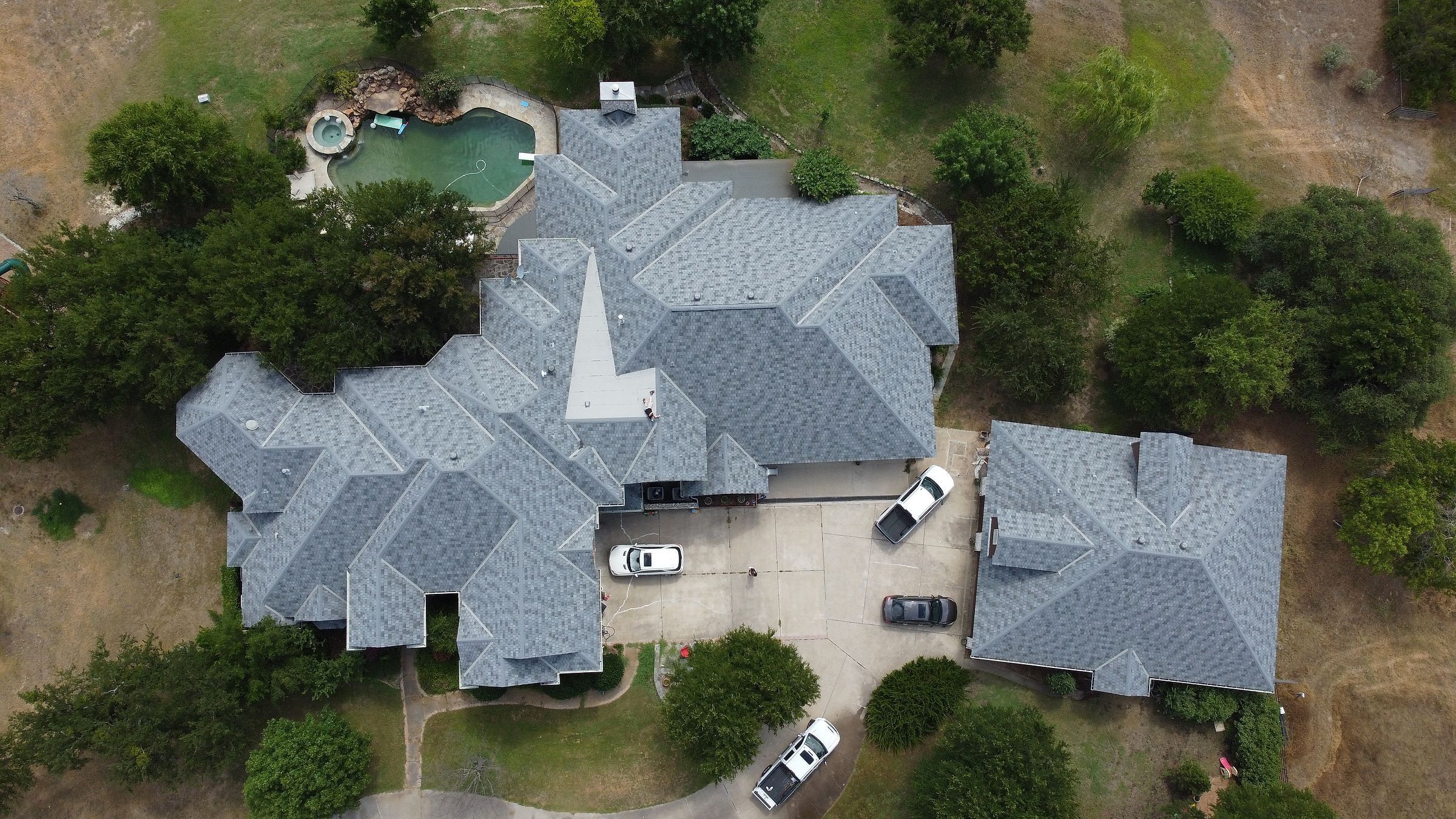 Gray shingle roof on a large home with a pool in Plano, TX, seen from directly above
