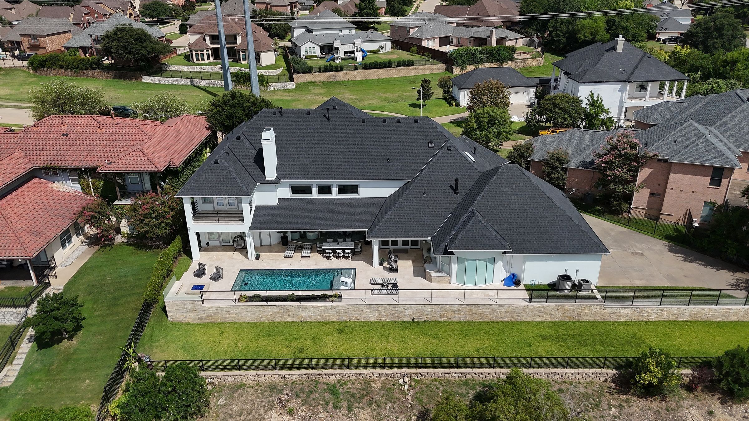 New charcoal shingle roof on a lakefront home, seen above the pool