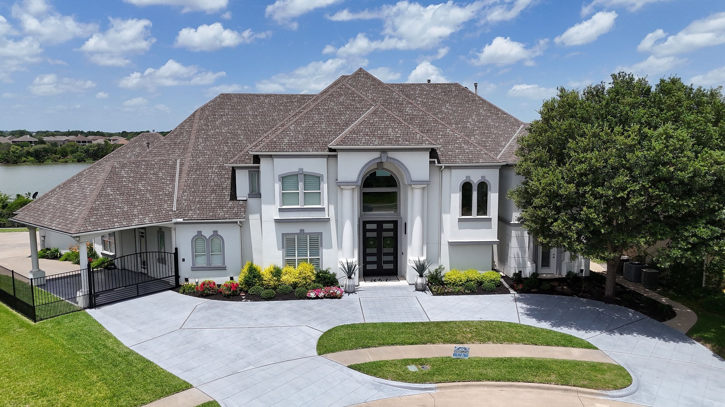White two-story home on Lake Arlington with a worn brown shingle roof
