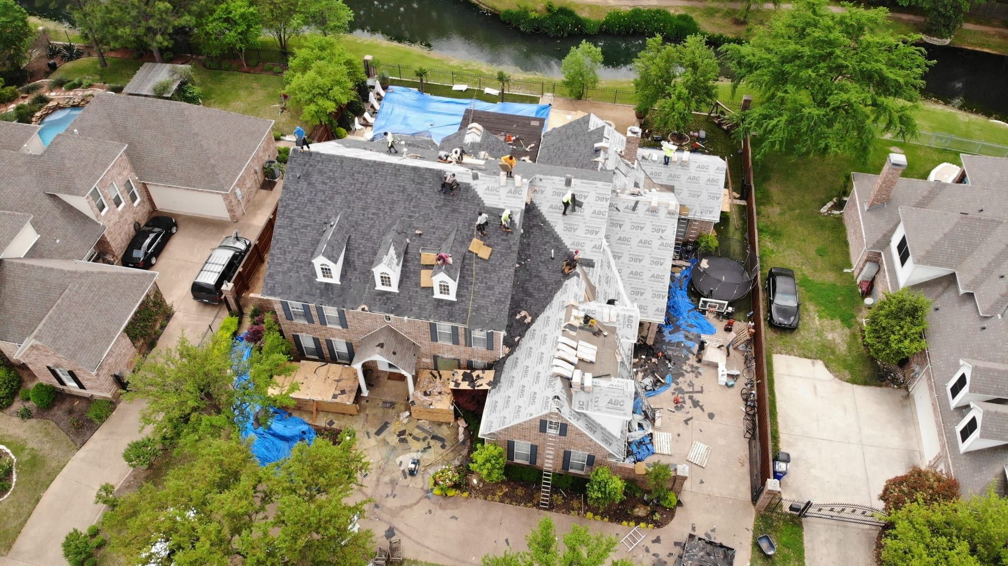Large two-story home during a full roof replacement, viewed from a drone