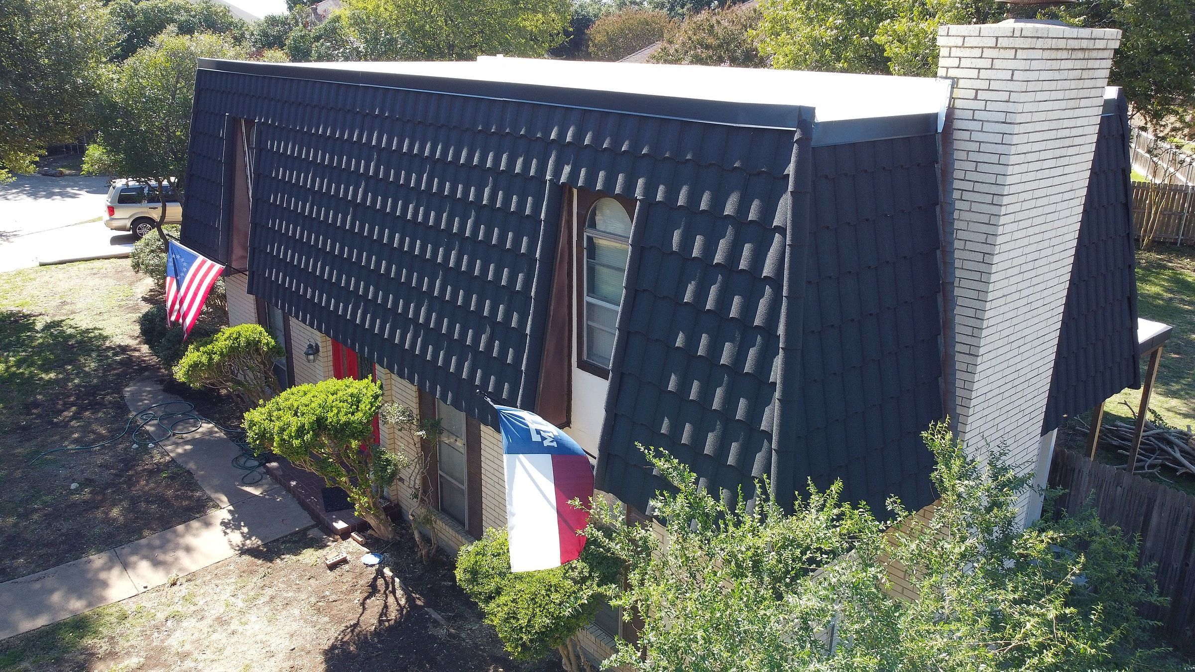 Stone-coated steel on the steep mansard sides and TPO on the low-slope top of a home, seen from above