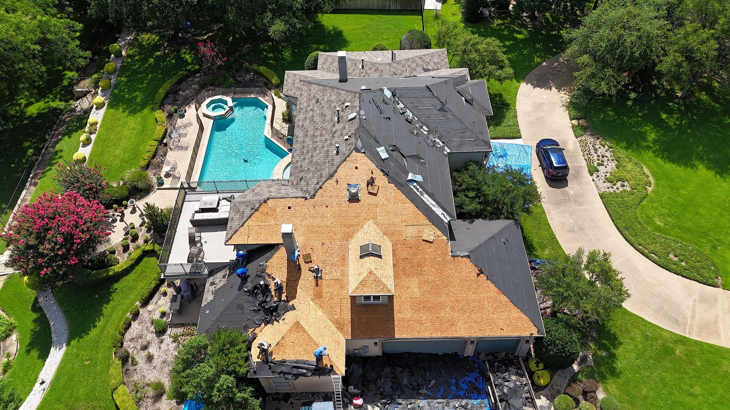 Crew tearing off old shingles on a stucco home with a pool in Mansfield, TX