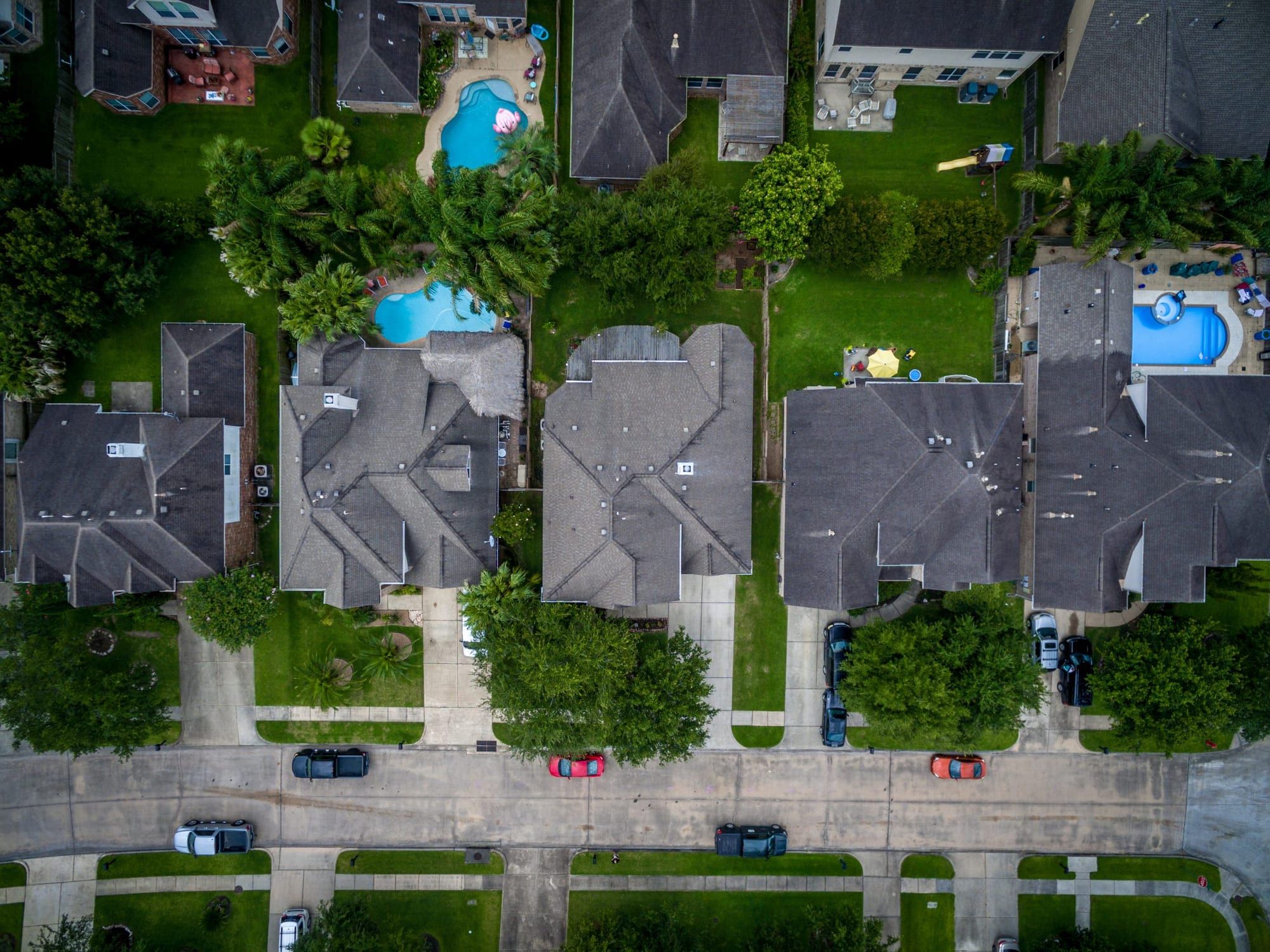 Row of neighborhood homes with new shingle roofs, seen from a drone