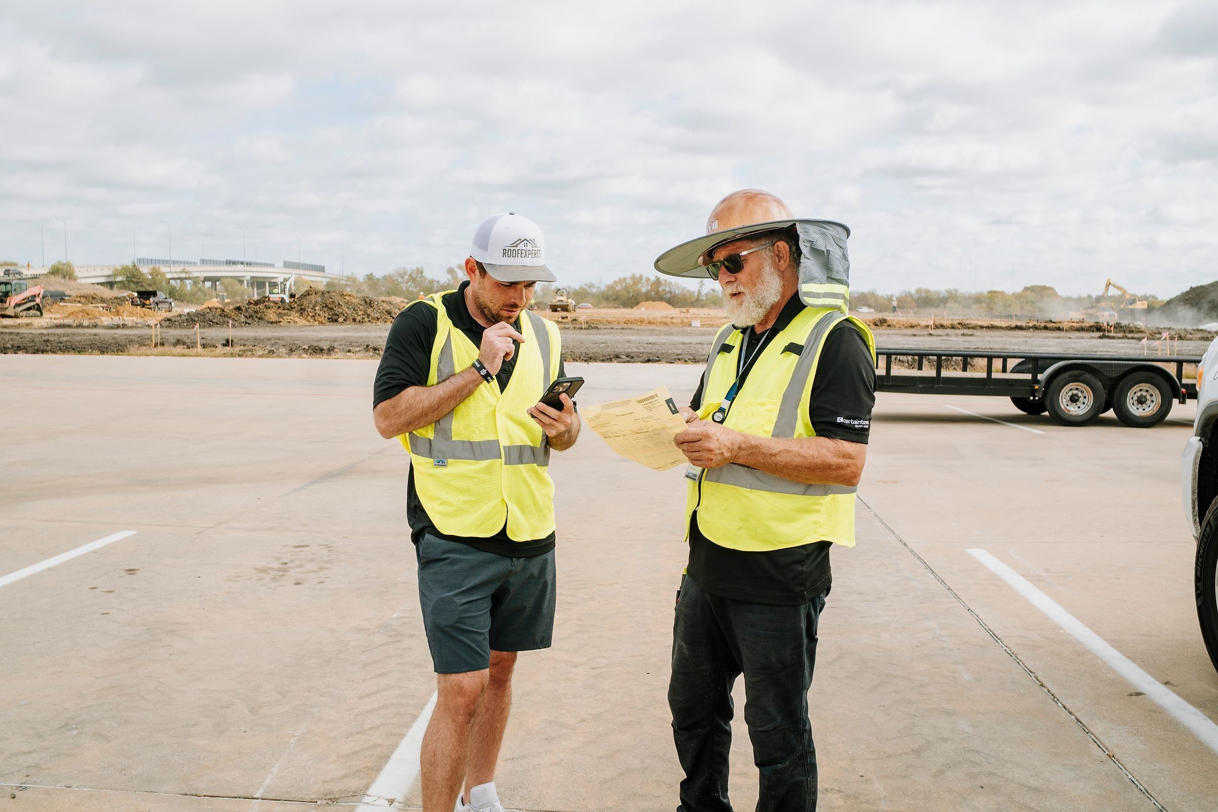 Roof Experts owner and crew foreman reviewing paperwork on a commercial job site