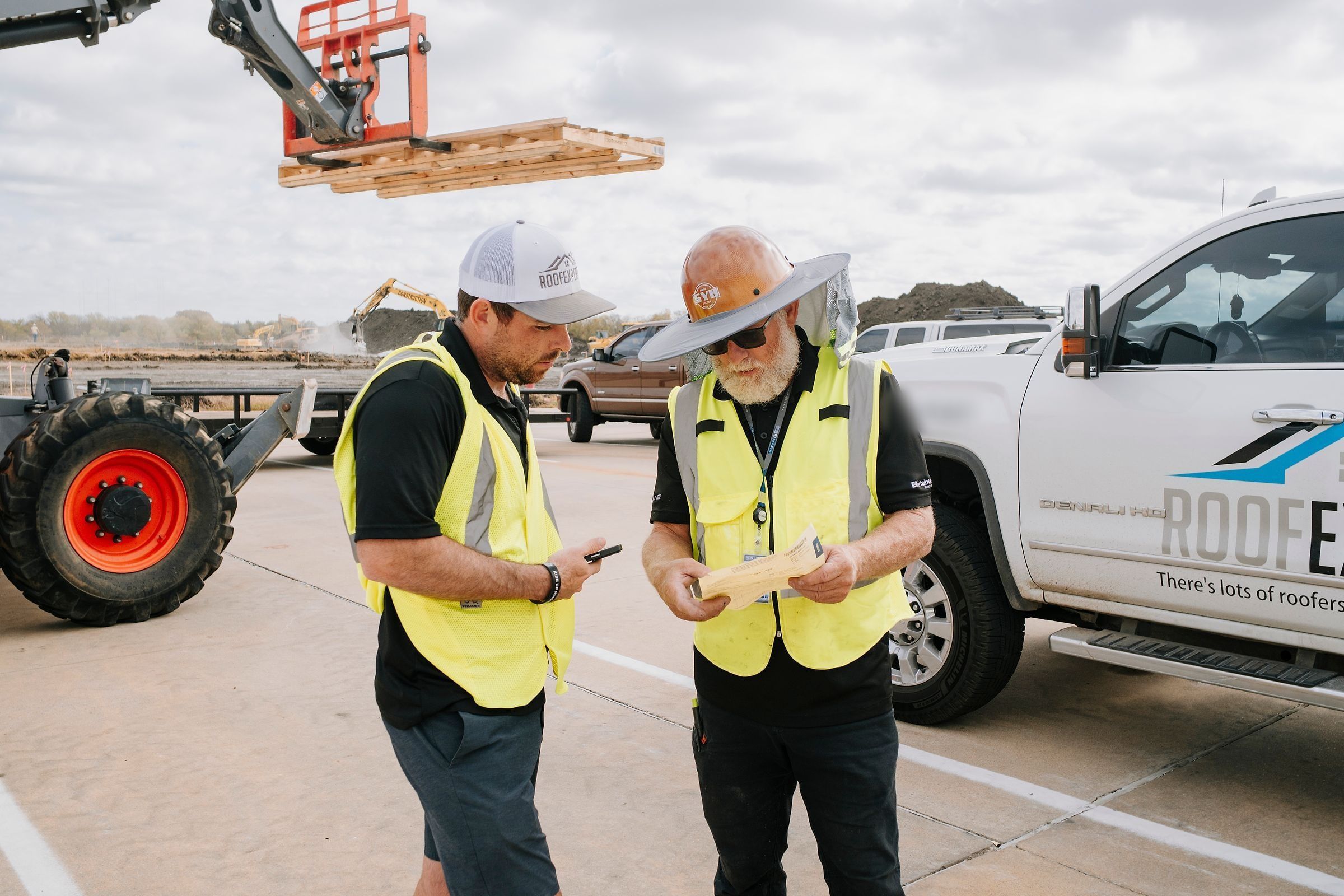Roof Experts owner and crew foreman going over plans beside the work truck