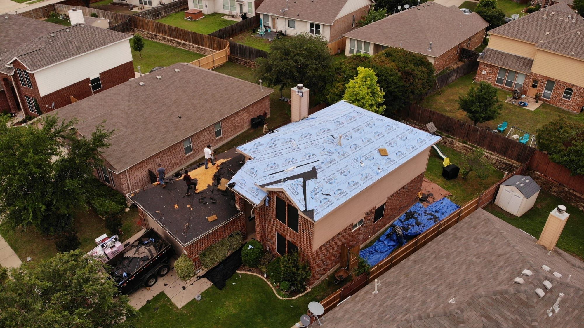 Brick home mid-replacement with the old shingles removed and new underlayment installed