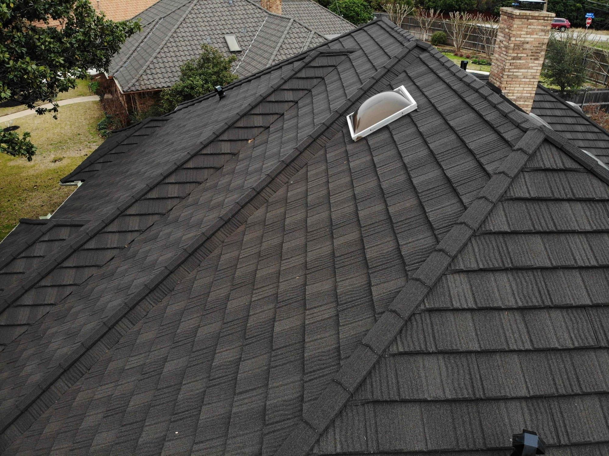 Stone-coated steel shake-profile roof panels and ridge around a skylight