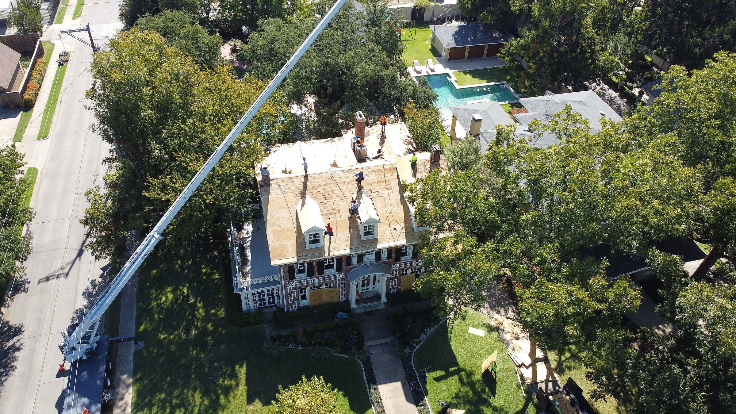 Boom lifting shingles to the roof of a two-story home