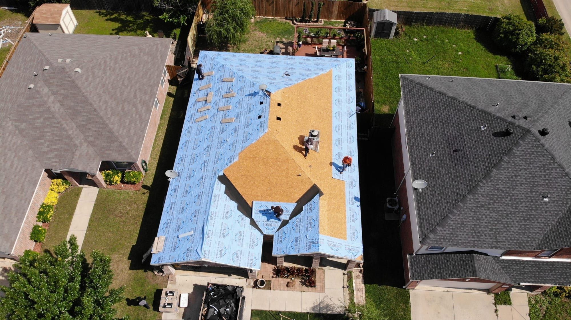 Roof tear-off in progress showing exposed wood decking and fresh underlayment