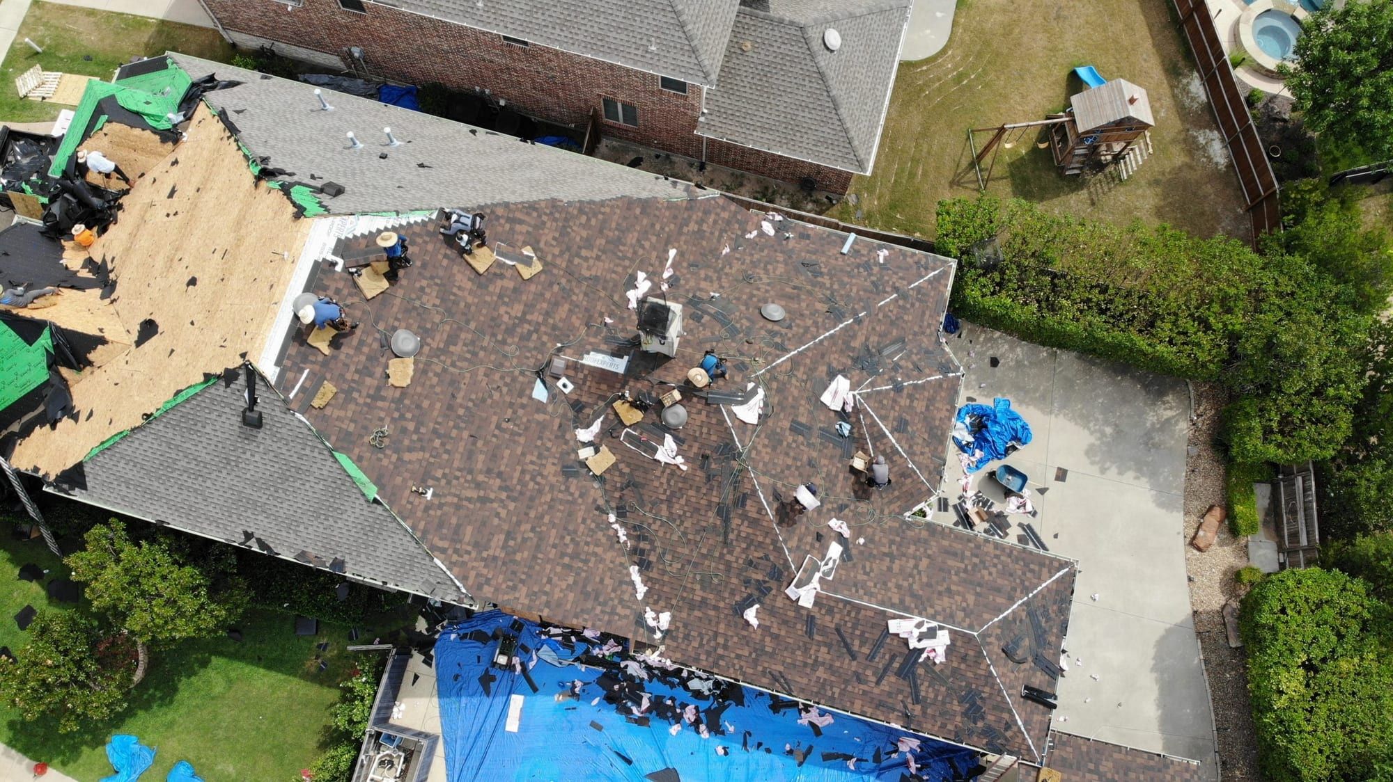 Crew partway through removing old shingles on a residential roof