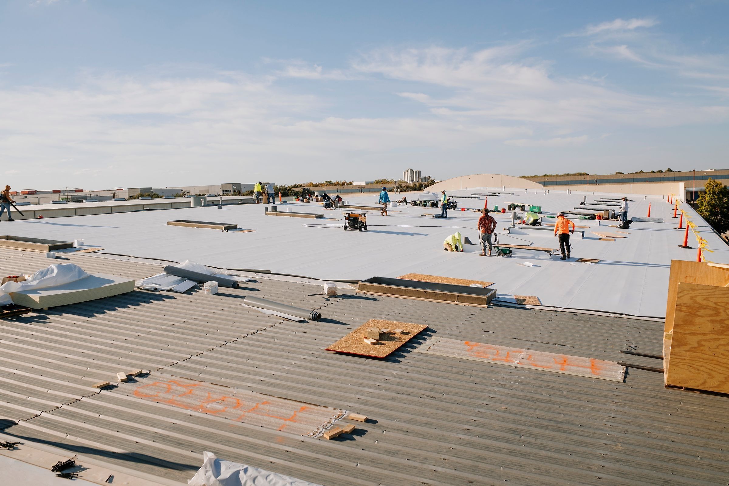 Roofing crew working across a large warehouse roof