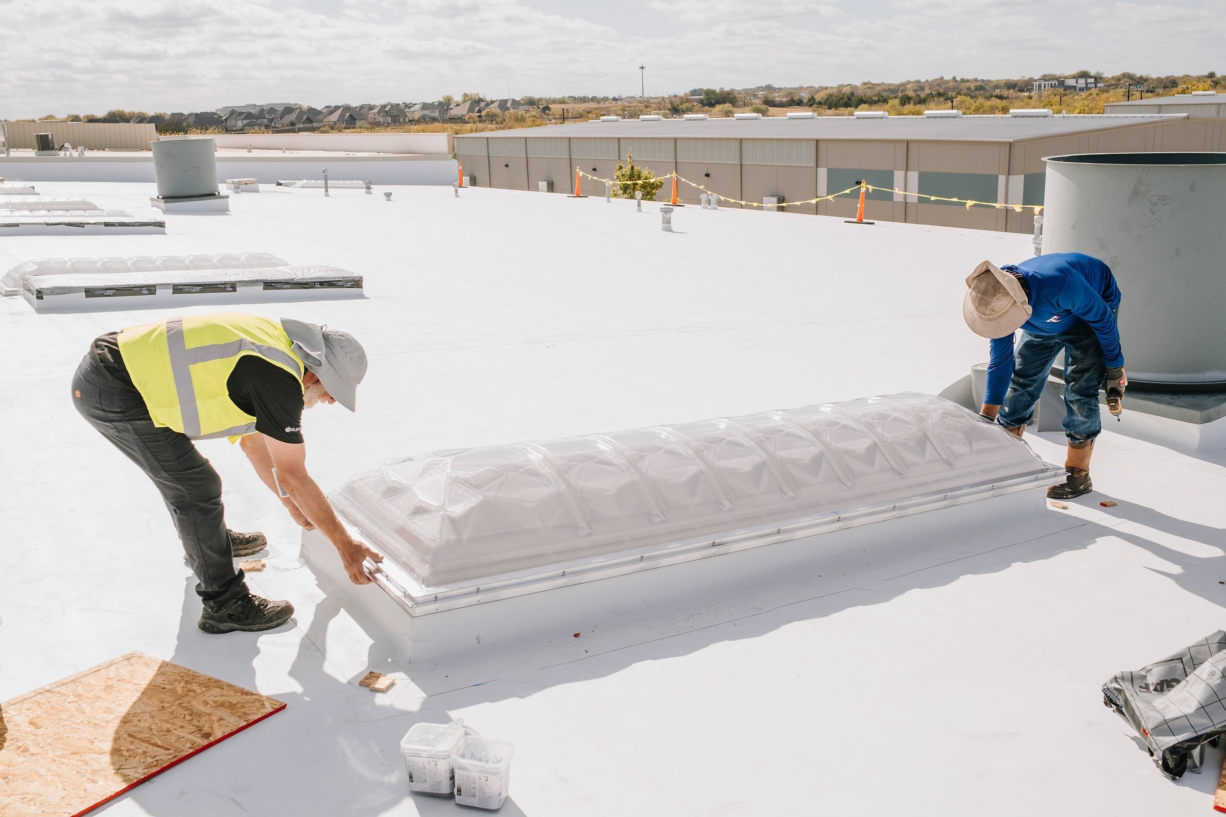 Roofer setting a skylight dome onto its curb