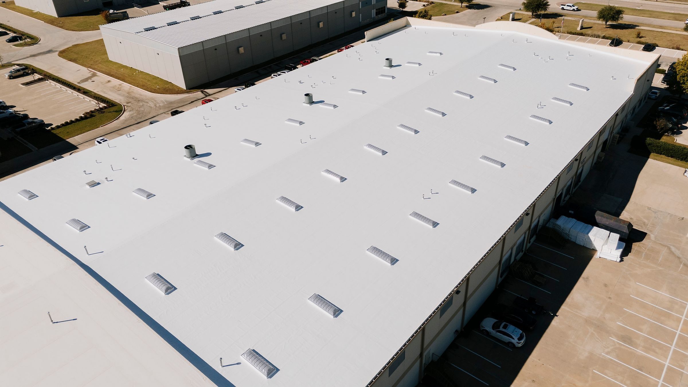 Finished white TPO warehouse roof with rows of skylights
