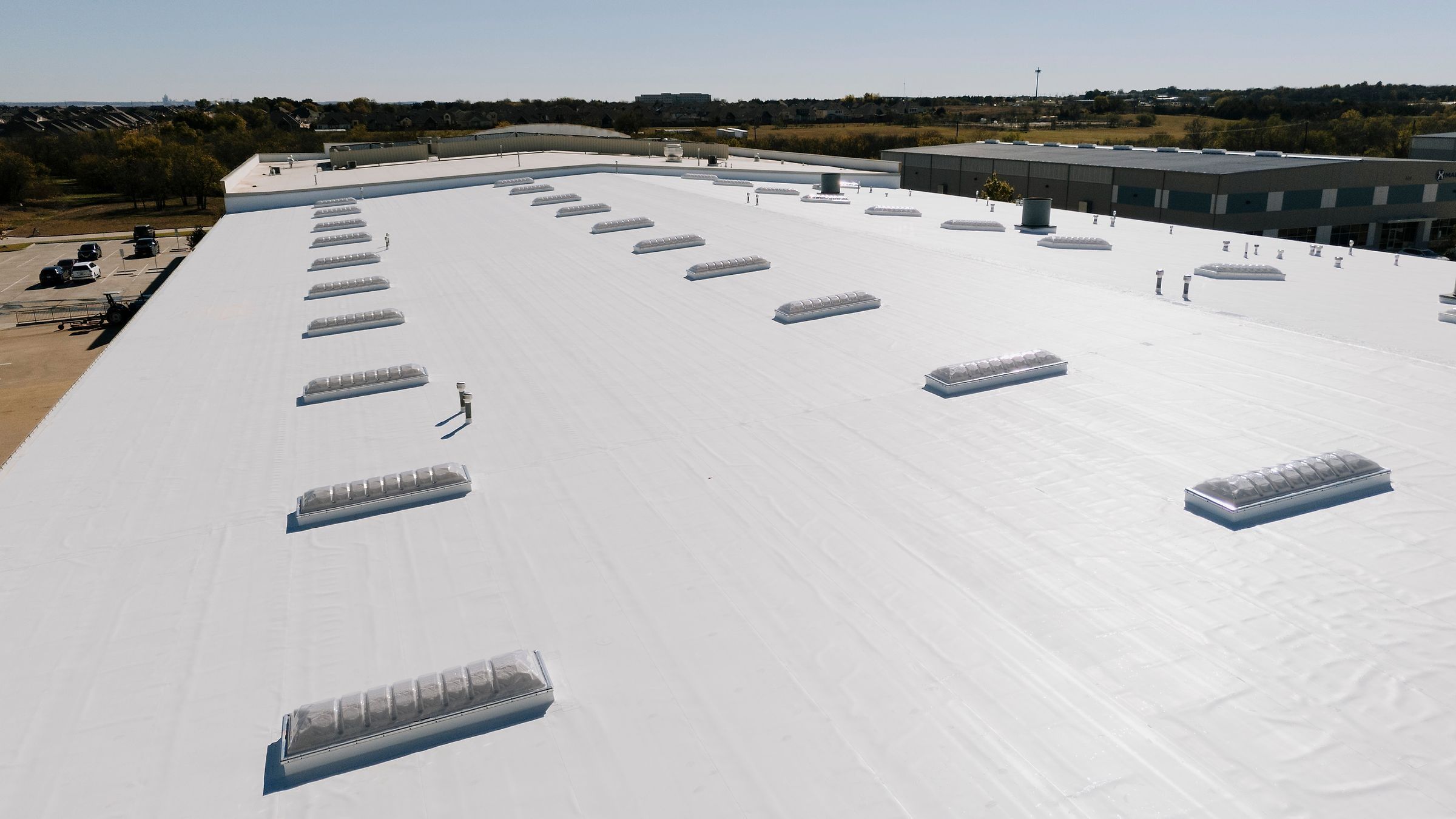 Finished white TPO warehouse roof and skylights, seen from a drone
