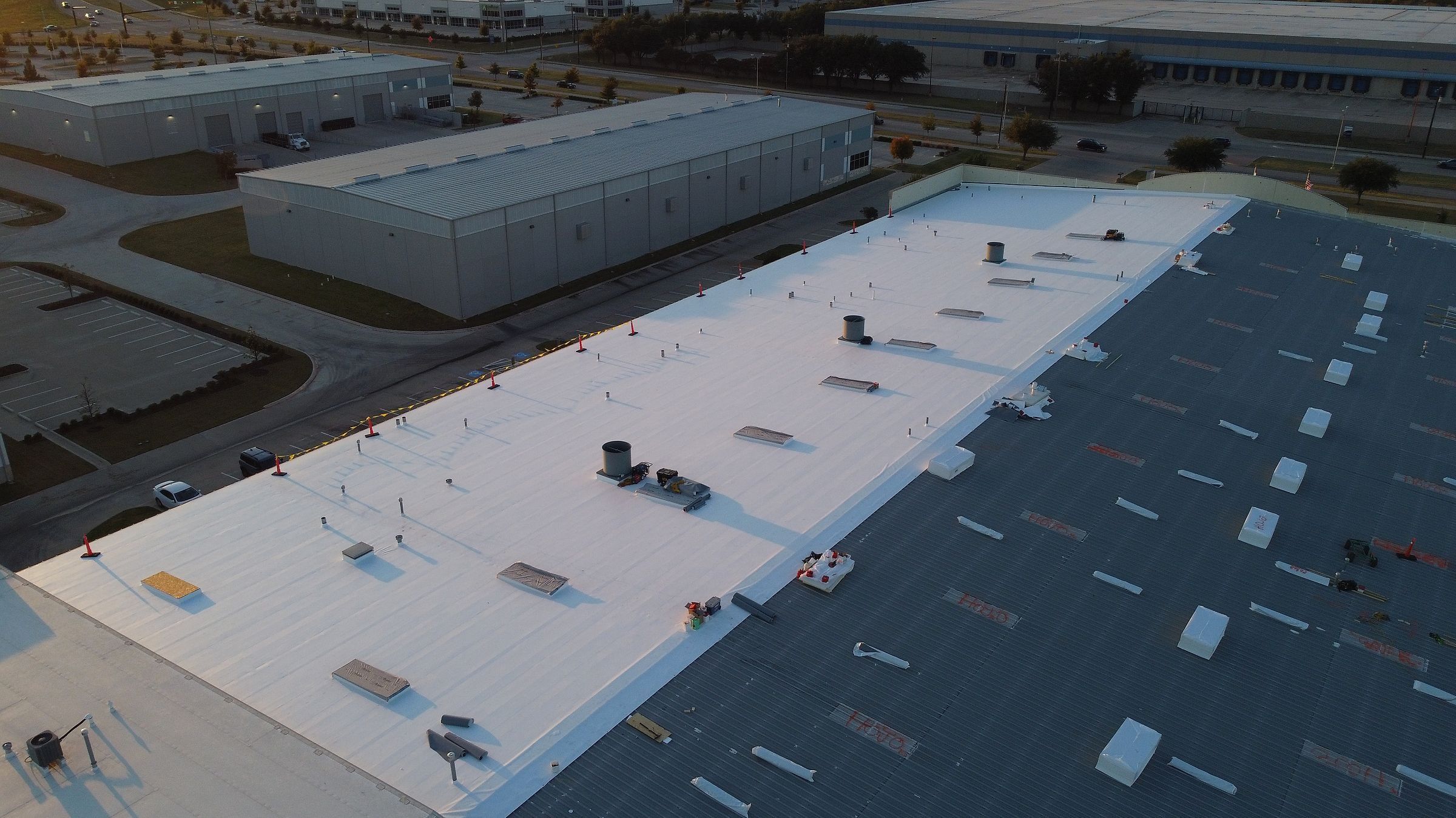 Commercial roof retrofit halfway done, white TPO beside the old metal roof