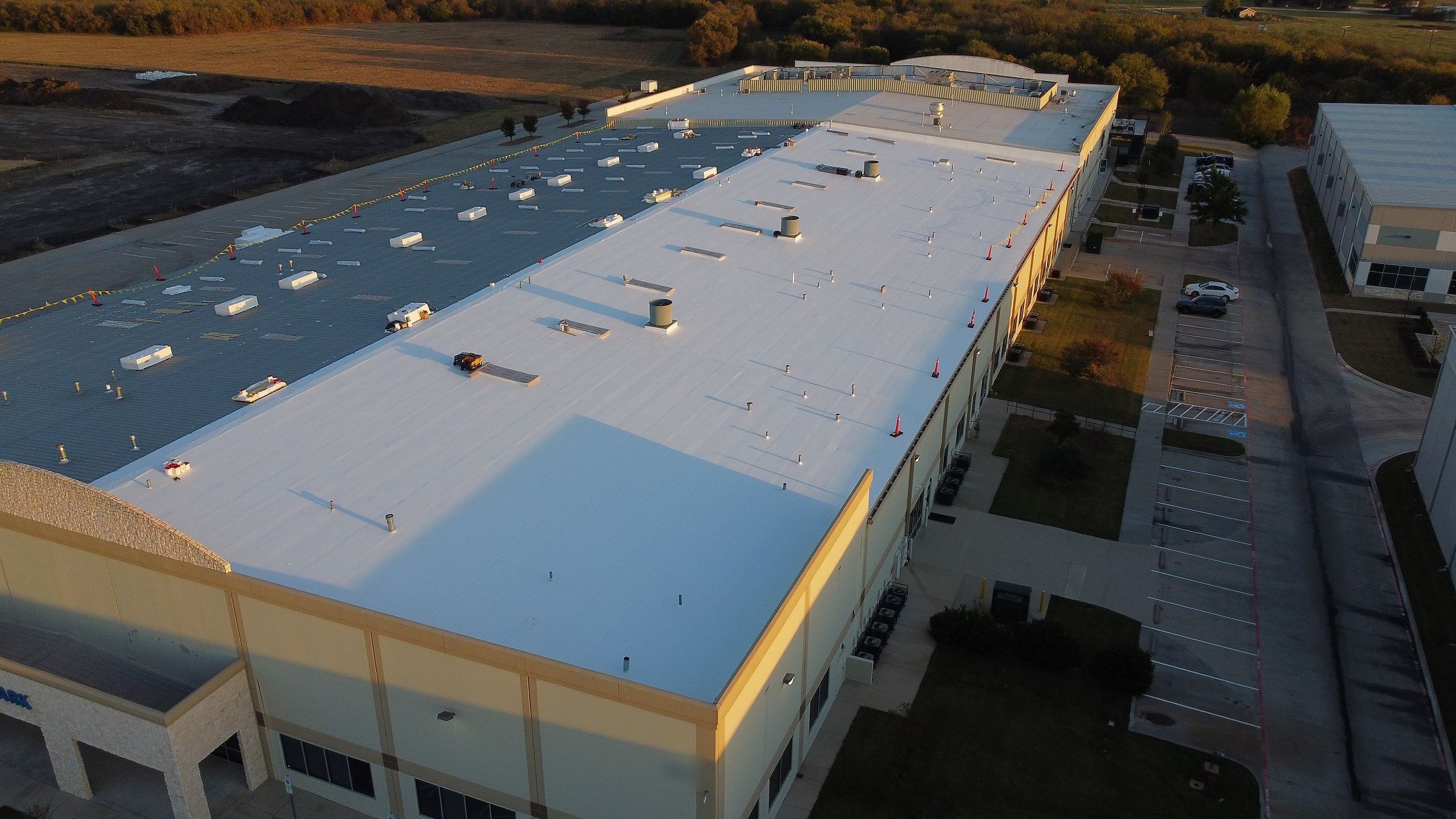 Warehouse in early morning light with a white TPO roof partly installed