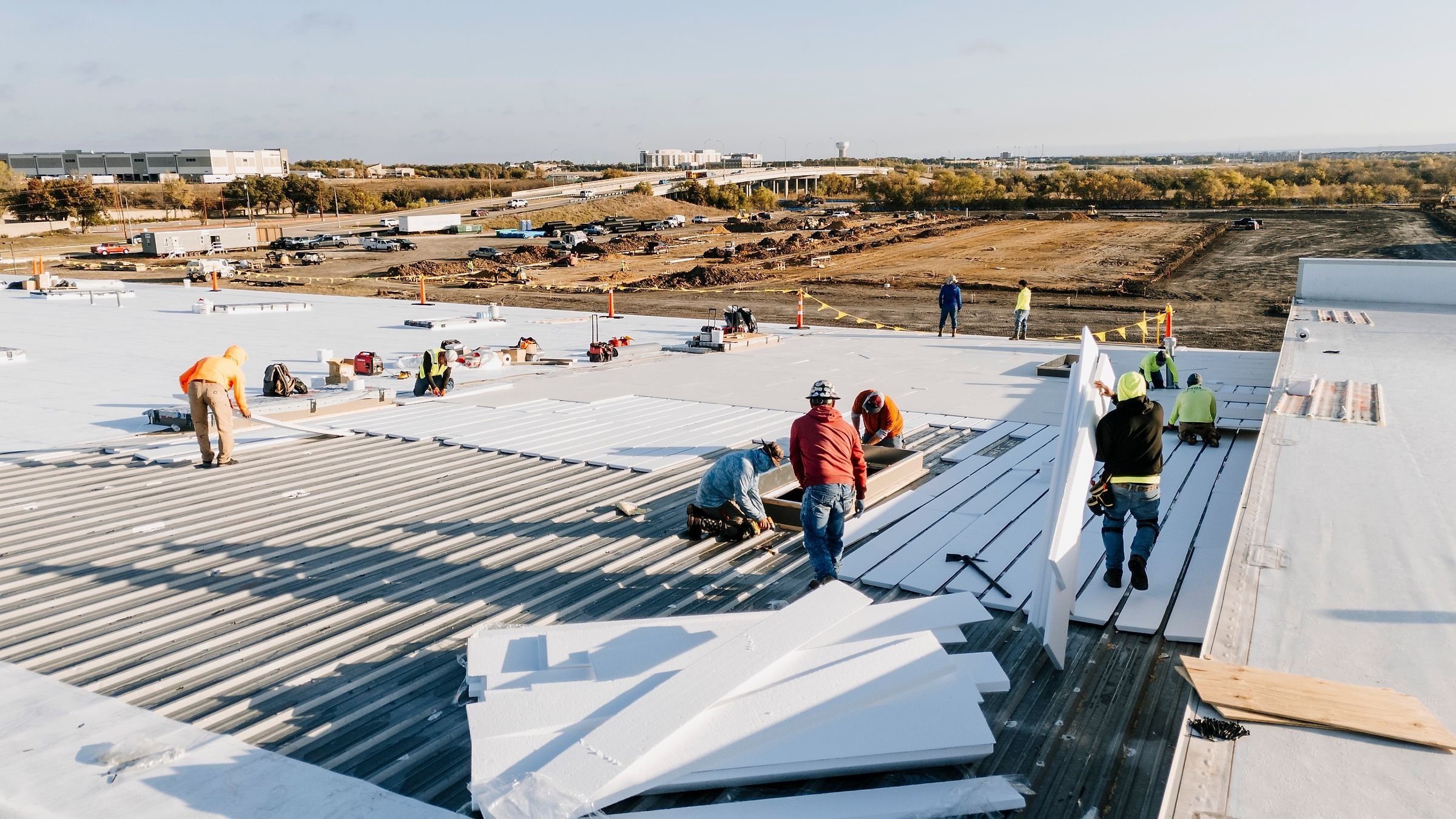 Insulation board over metal roof panels, with new white TPO beyond