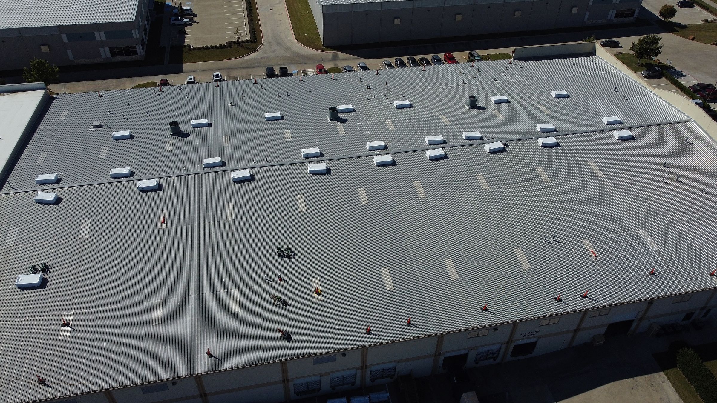 Roofing materials staged on an old R-panel metal warehouse roof
