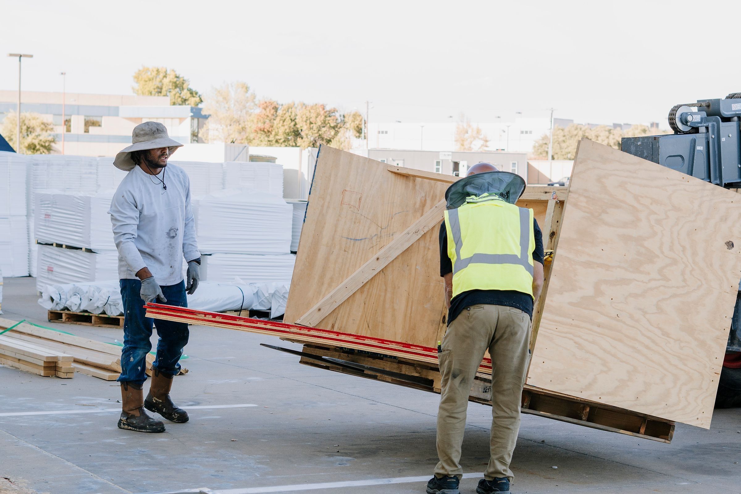 Two roofers carrying a crated skylight across a parking lot