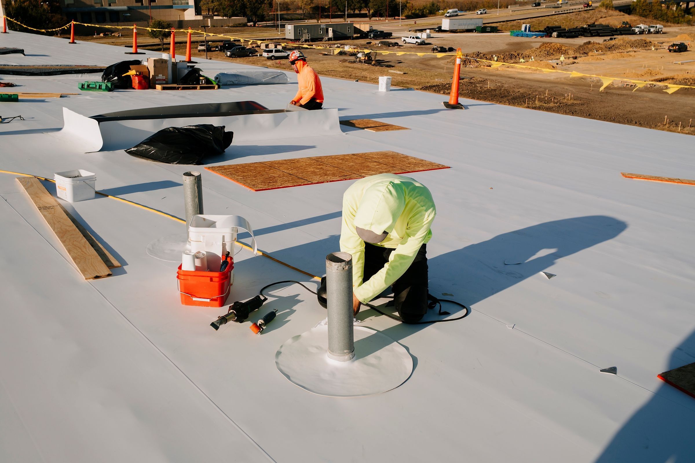 Roofer flashing a pipe penetration on a white TPO roof