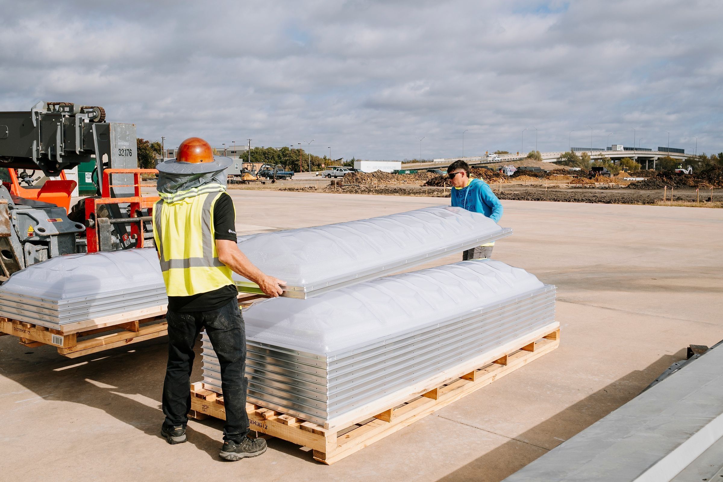 Crew unloading stacked skylight domes from a pallet