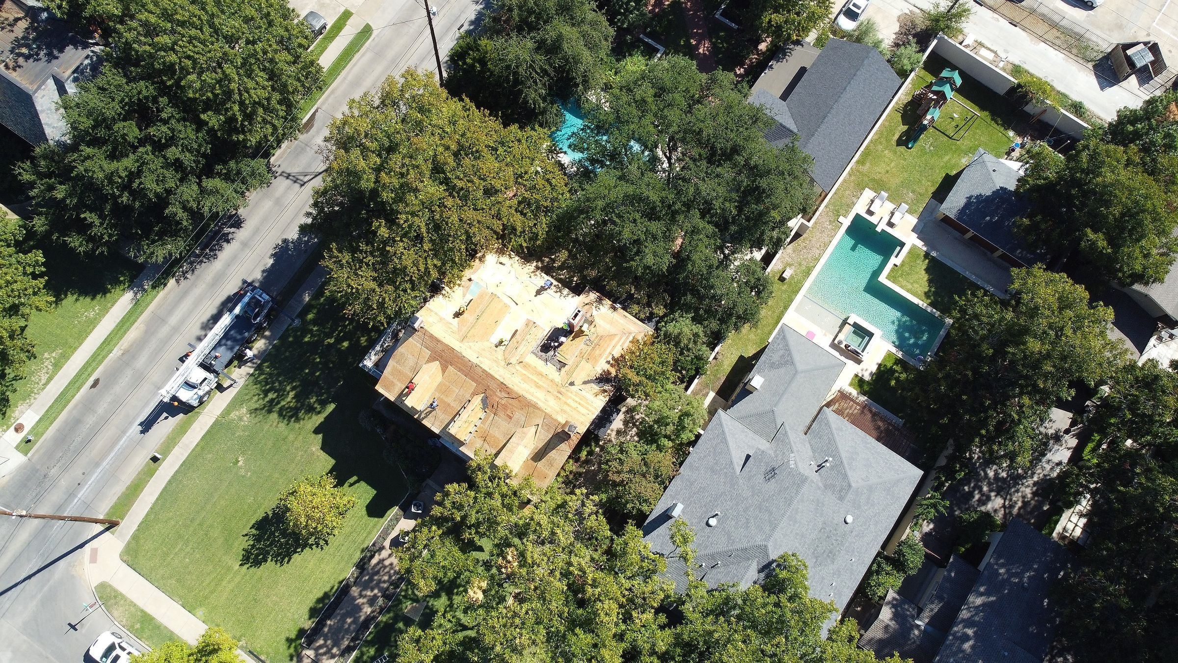 Two-story home with the old roof off and the decking exposed, seen from above
